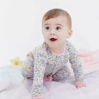 Baby wearing a floral onesie on a light pink background