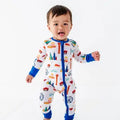 Toddler wearing Convertible Footies - Bamboo - Blue Chicago with colorful Chicago-themed illustrations, standing and smiling on a white background, showcasing breathable baby fabrics and cozy baby essentials.