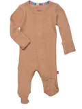 A baby's long-sleeve footed sleeper in a warm tan color, featuring a waffle knit texture, snap closures down the front, and a small red tag on the side.