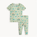 A two-piece baby pajama set featuring a short-sleeve top and matching long pants in a light sage green color, both printed with a playful golf course pattern of golf carts, trees, and golf balls. The set is laid flat against a clean white background.