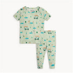 A two-piece baby pajama set featuring a short-sleeve top and matching long pants in a light sage green color, both printed with a playful golf course pattern of golf carts, trees, and golf balls. The set is laid flat against a clean white background.