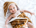 Baby wrapped in a brown and white striped towel on a white blanket