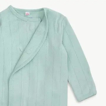 A close-up of a light mint green knit baby wrap cardigan with long sleeves and a soft textured pattern, shown against a plain off-white background.