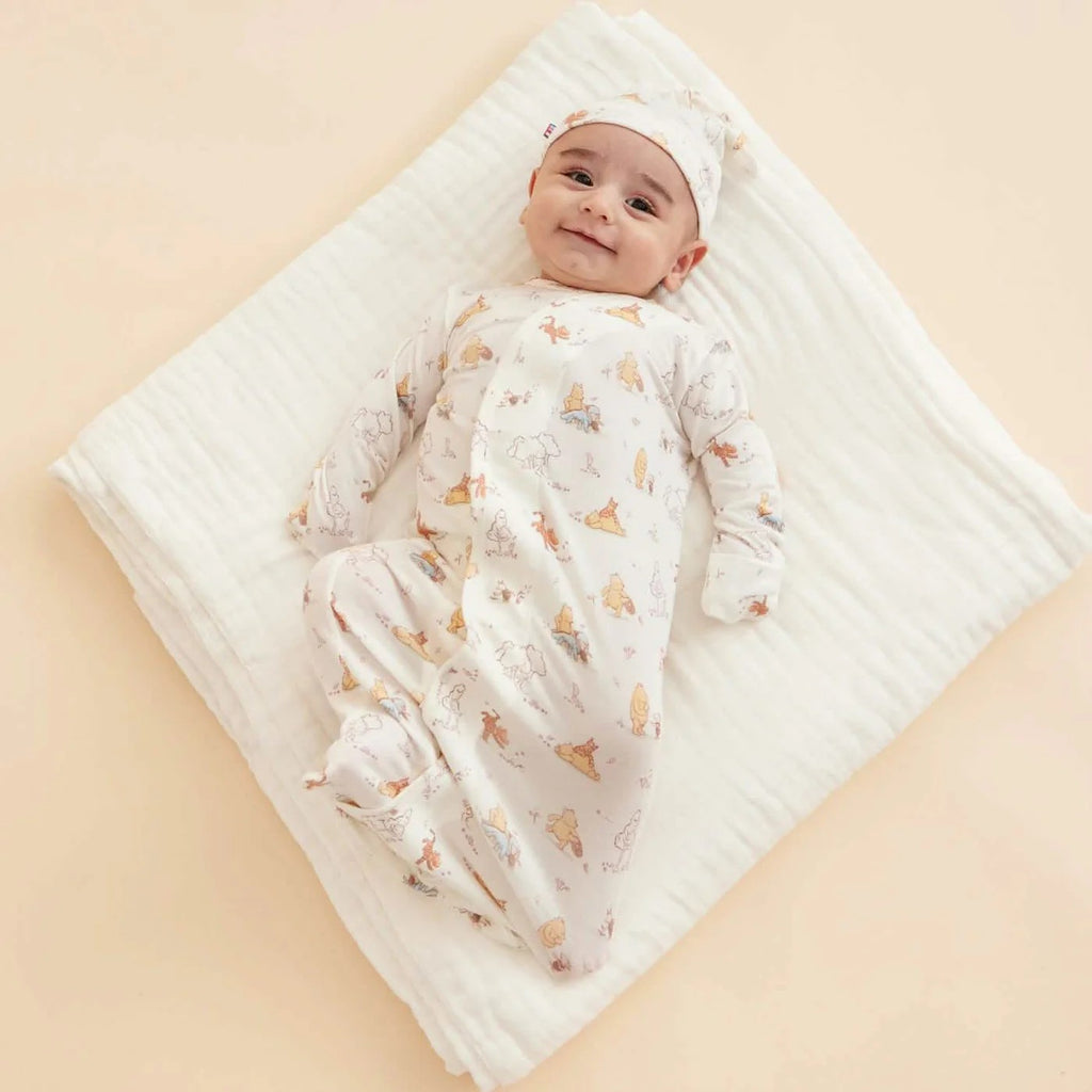 Baby lying on a quilted blanket wearing a patterned outfit and hat.