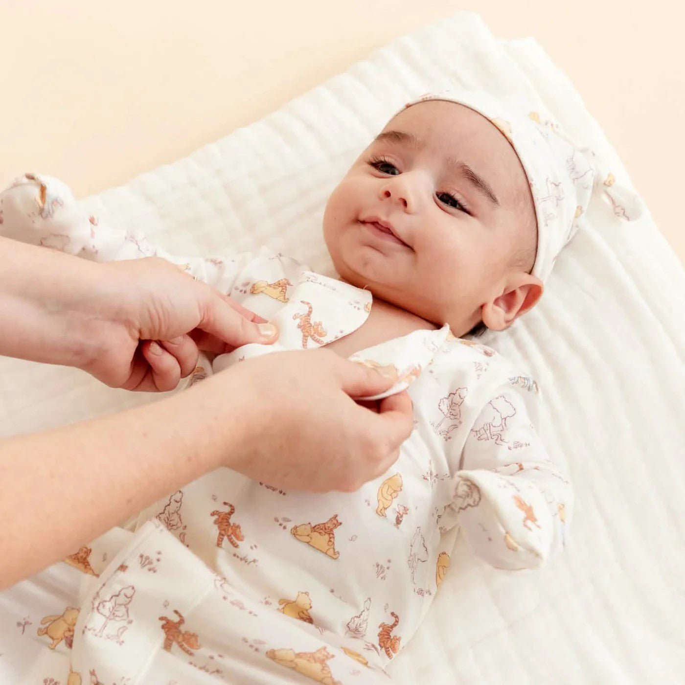 Baby wrapped in a white blanket with animal patterns, being held by a person.