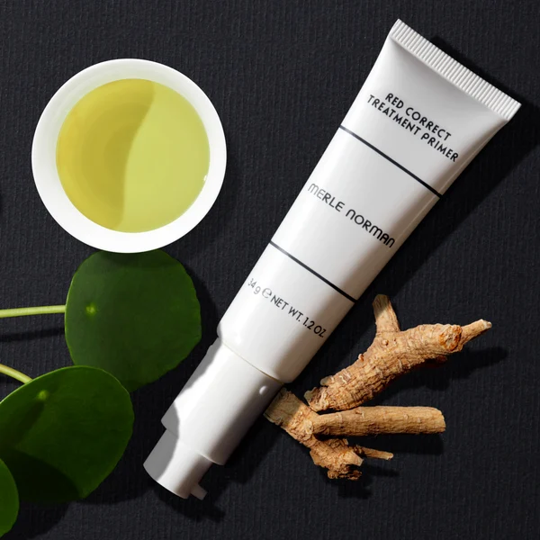 Tube of Red Correct Treatment Primer displayed with natural elements like green leaves and roots, highlighting calm, stylish essentials for moms and kids.