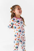Smiling young girl wearing colorful Two-Piece Pajamas - Bamboo - Pink Chicago featuring playful Chicago-themed illustrations in soft bamboo fabric, perfect for cozy nights.