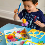A young child playing with the "My Very First Games - Here, Fishy, Fishy! Magnetic Game," using a magnetic fishing rod to catch colorful wooden fish on a bright play table, promoting imaginative learning and sensory play.