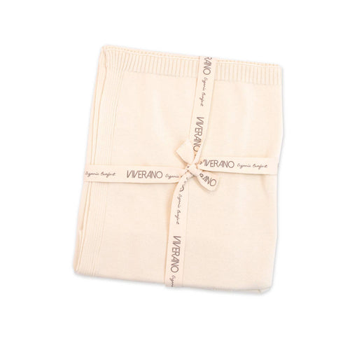 Folded cream-colored baby blanket tied with a branded ribbon, showcasing Viverano Organics - Milan Pastel Baby Blanket Sweater Knit (Organic Cotton): Cream, perfect for stylish kids clothing and cozy baby essentials.