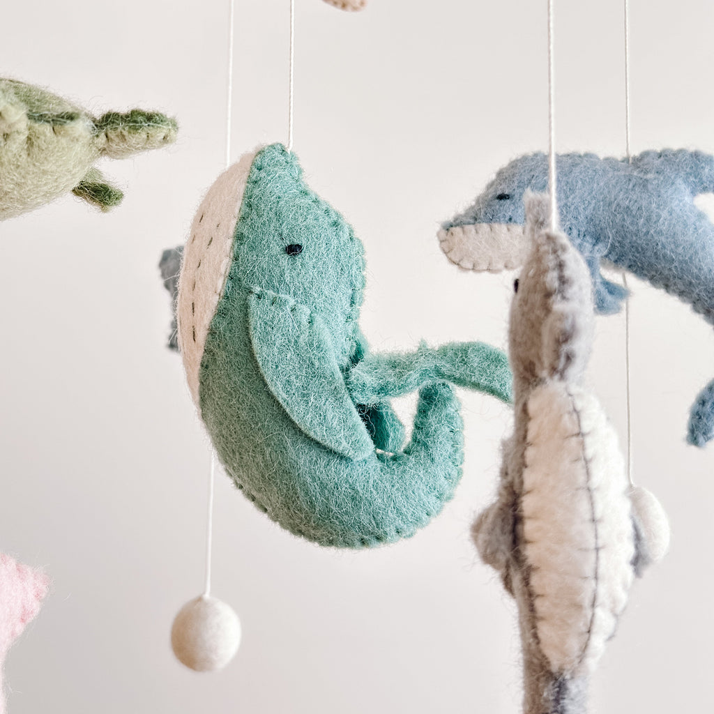 Close-up of handcrafted felt sea life animals including a whale, dolphin, and turtle hanging from strings in the Mobile - Felt Baby - Sea Life, perfect for a cozy baby nursery.