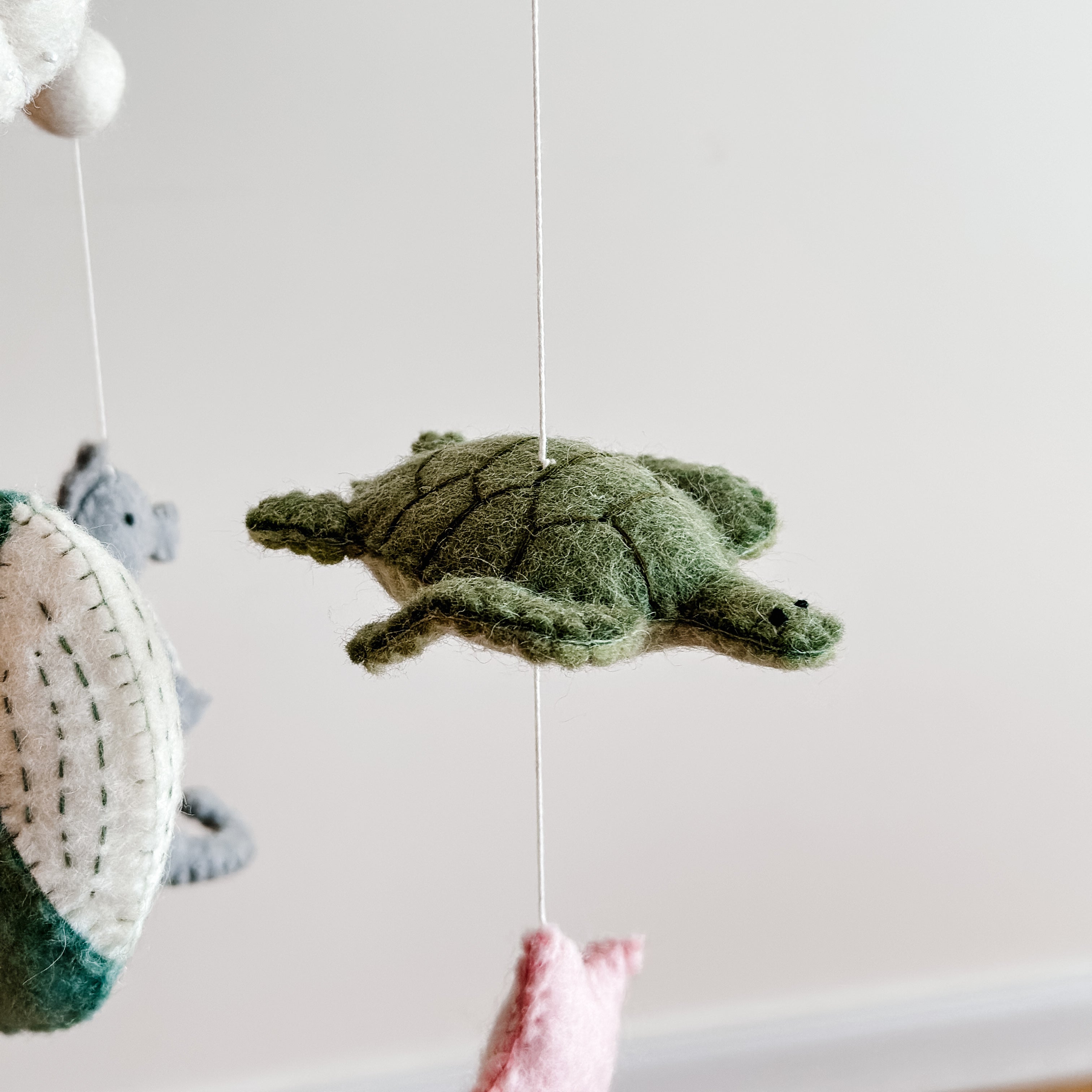 Close-up of a green felt sea turtle hanging as part of the Mobile - Felt Baby - Sea Life, a soft, natural baby accessory from a curated children’s boutique focused on stylish essentials for little ones and moms.