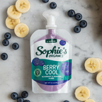 Sophie's Organics - Cool (6 Pack) blueberry and banana puree pouch surrounded by fresh banana slices and blueberries, showcasing a cozy baby essential from a curated children’s boutique.