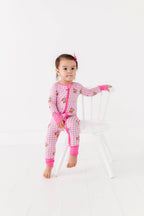 Child wearing a pink and white checkered outfit with pink gloves on a white background