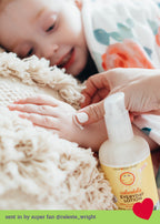 Close-up of a child’s hand receiving a gentle application of California Baby - Calendula™ Everyday Lotion from a caregiver, surrounded by soft, cozy textures, reflecting a nurturing moment consistent with a curated children’s boutique ethos.