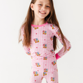 Young girl wearing a pink checkered outfit with cartoon characters on a white background