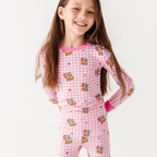 Young girl wearing a pink checkered outfit with cartoon characters on a white background