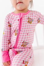 Child wearing a pink checkered outfit with 'Little Sis' text on a white background