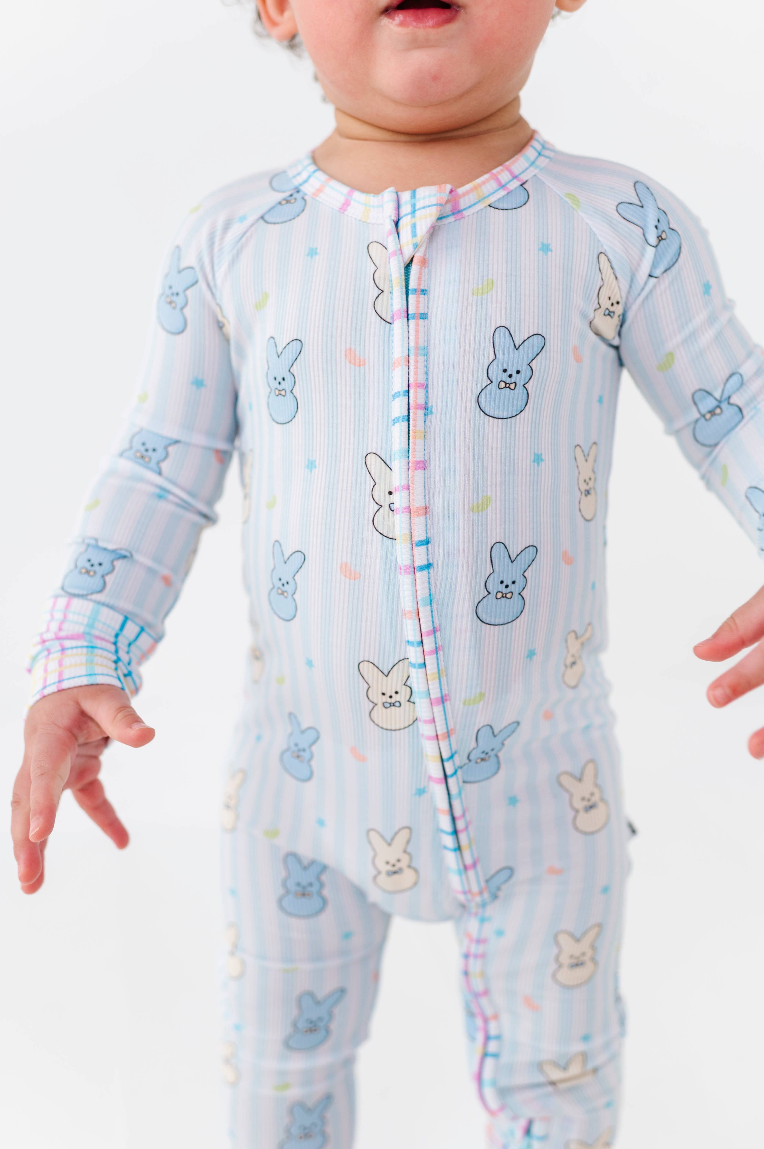 Toddler wearing Kiki + Lulu - Peeps + Sleeps Convertible Footies with pastel striped fabric and playful bunny prints, showcasing cozy baby essentials from a curated children’s boutique.