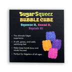 A square black product box or packaging card for 'Sugar Squeez Bubble Cube' with colorful text and illustrations of four bubblegum-style cubes in blue, orange, yellow, and pink on a white background.