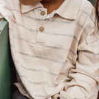 Close-up of a person wearing a beige striped shirt with buttons.