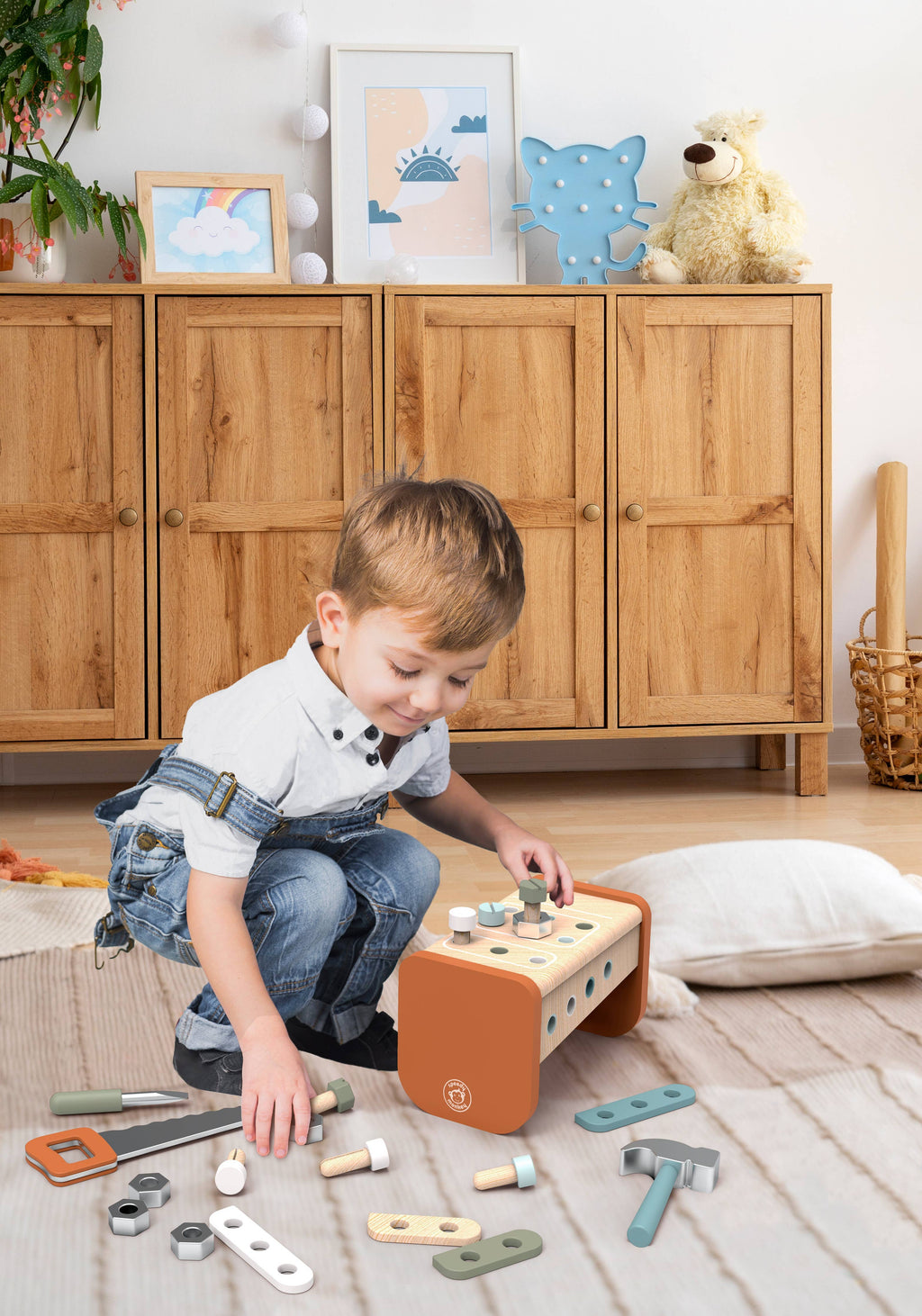 A young child playing on the floor with the Speedy Monkey - Toolbox - Workbench, surrounded by colorful wooden tools and parts in a cozy, stylish children’s room setting.