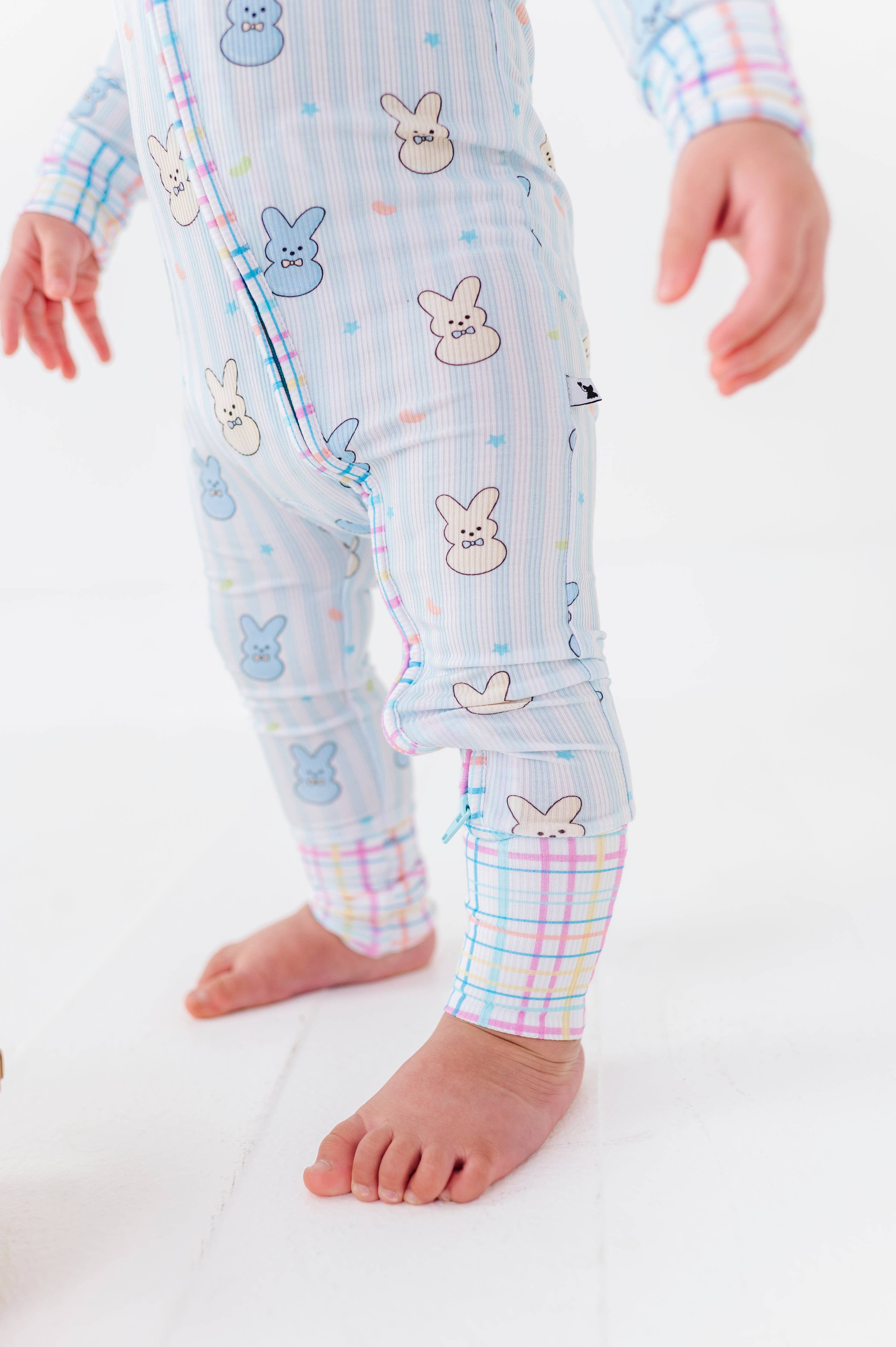 Baby wearing Kiki + Lulu - Peeps + Sleeps Convertible Footies featuring soft pastel colors with playful bunny and star prints, designed for comfort and style in a curated children’s boutique.