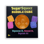 Sugar Squeez Bubble Cube product packaging on a white background. The black square box features a circular cutout showing the translucent orange-brown bubble cube inside, with colorful illustrations of squeeze gummy bears on each side and playful text.