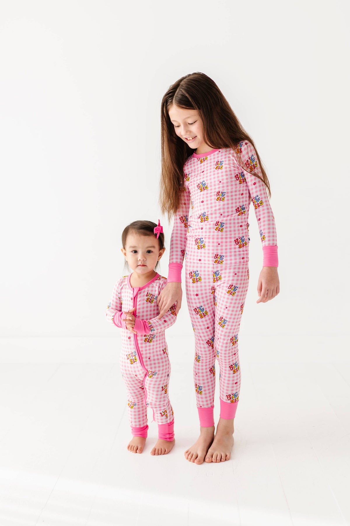 Two children wearing pink pajamas with cartoon characters on a white background