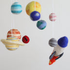 Mobile - Felt Baby - Solar System with soft felt planets and a rocket ship hanging to inspire imaginative play and sensory learning in a cozy nursery setting.