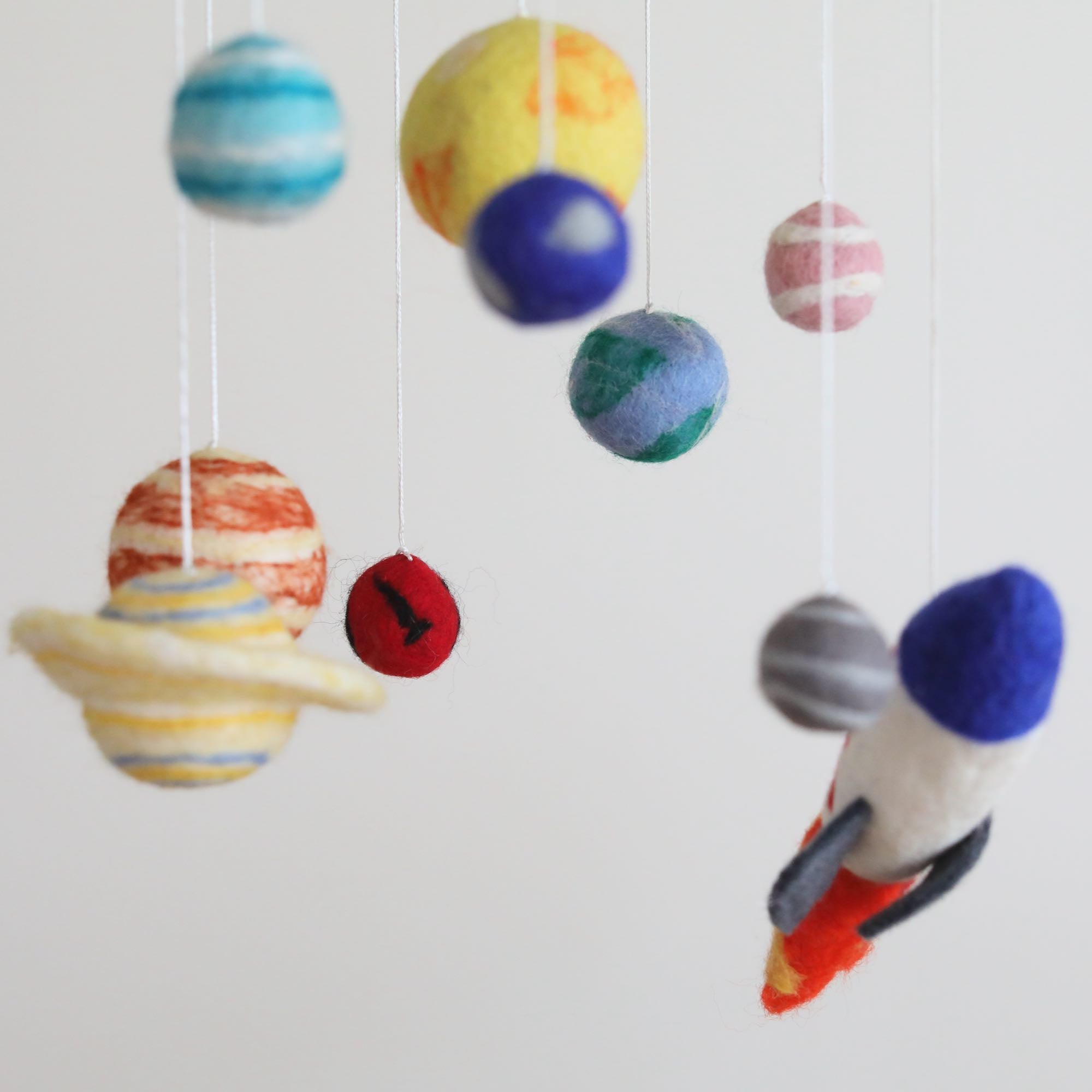 Mobile - Felt Baby - Solar System with soft felt planets and a rocket ship hanging to inspire imaginative play and sensory learning in a cozy nursery setting.