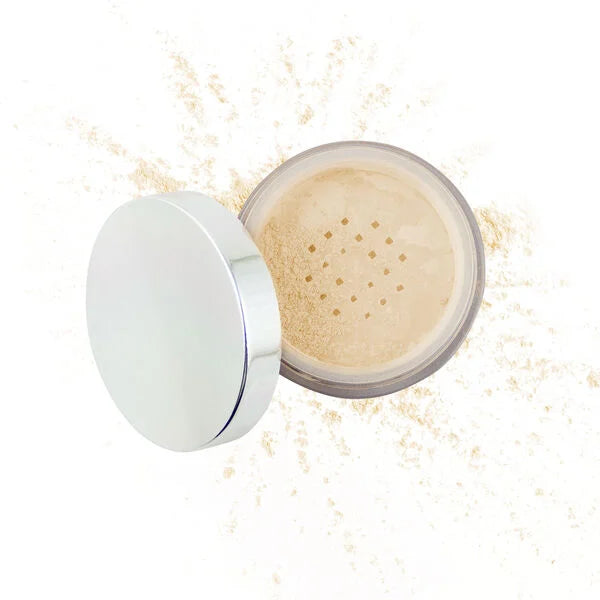 Open container of Merle Norman Cosmetics - Flawless Effect Loose Powder in a light neutral shade with silver lid, fine powder scattered around, showcasing a smooth finish.