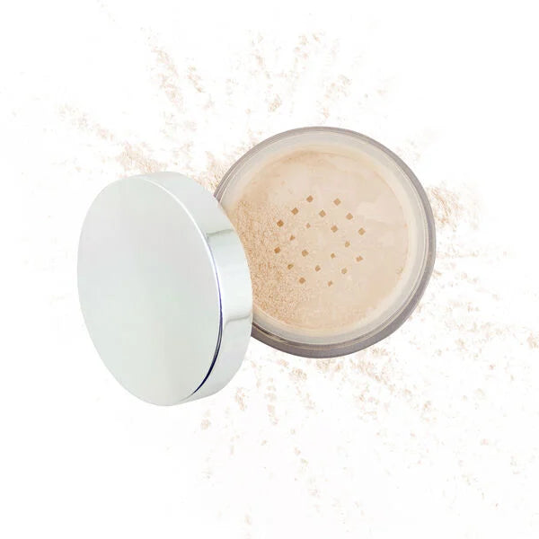 Open container of Merle Norman Cosmetics - Flawless Effect Loose Powder with spilled translucent powder on a white background, showcasing a soft neutral cosmetic product.