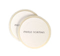 Two round, soft pressed powder puffs with textured surfaces and the brand name Merle Norman printed on them, ideal for flawless makeup application. Merle Norman Cosmetics - Pressed Powder Puffs.