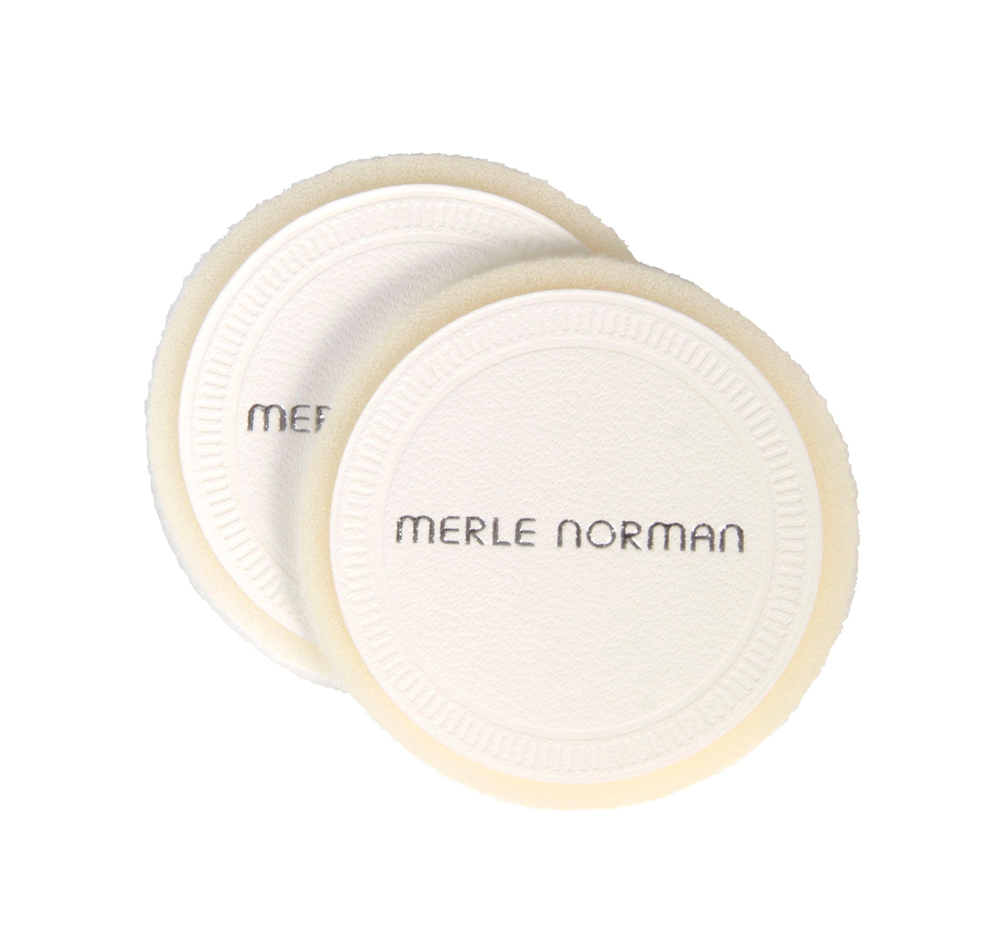 Two round, soft pressed powder puffs with textured surfaces and the brand name Merle Norman printed on them, ideal for flawless makeup application. Merle Norman Cosmetics - Pressed Powder Puffs.