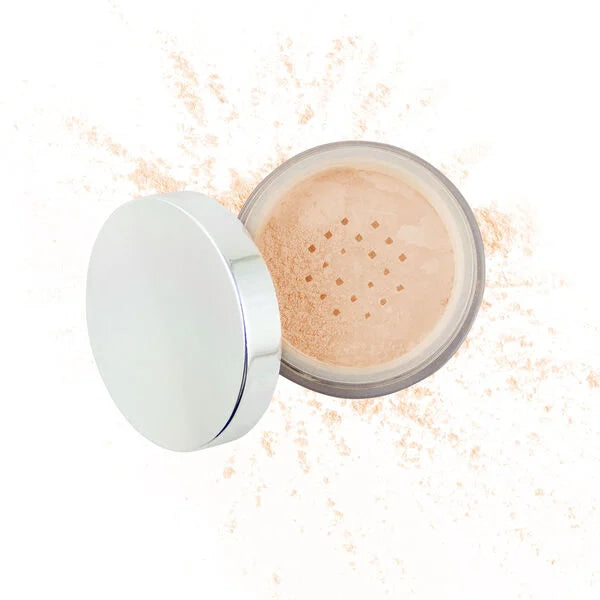 Open jar of loose light beige mineral powder makeup with silver lid and scattered powder around it, showcasing Purely Mineral Makeup.