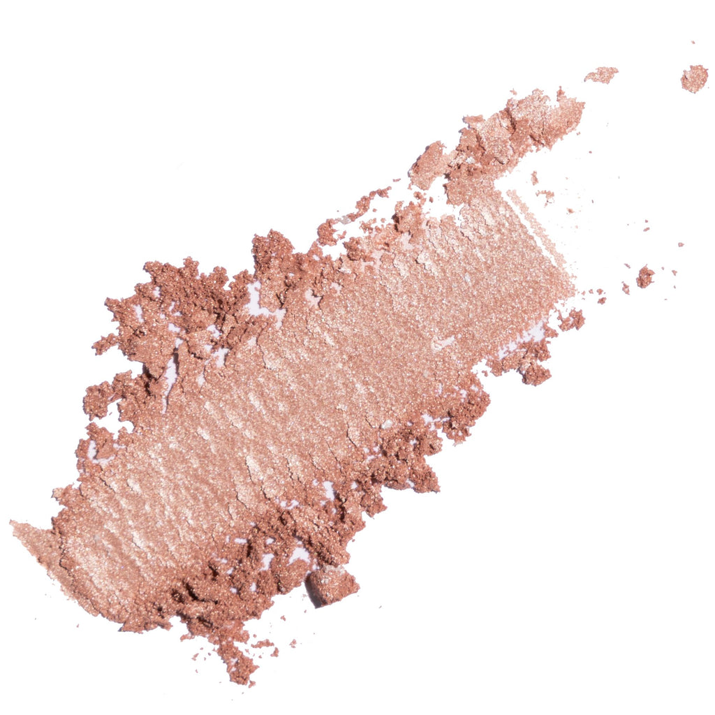 A textured swipe of shimmery rose gold makeup powder, showing both the pressed pigment texture and the creamy, blended stroke, set against a solid white background.