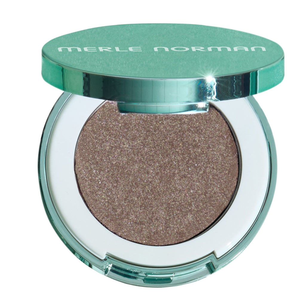 Merle Norman eyeshadow compact with a metallic teal-green lid and a shimmering taupe-brown eyeshadow pan, shown open on a white background.