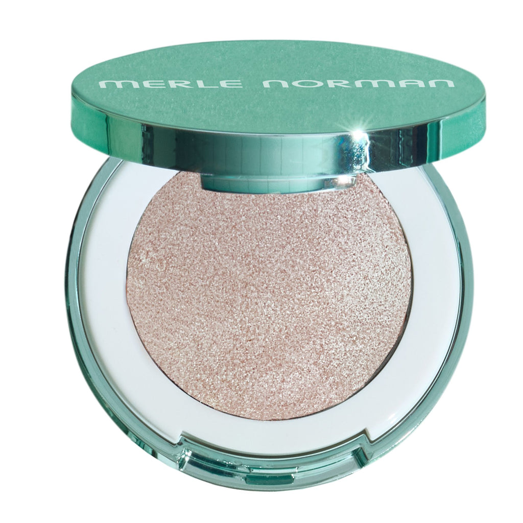 Merle Norman eyeshadow compact with a shimmering light pinkish-beige shadow and a metallic teal-green lid, shown on a white background.