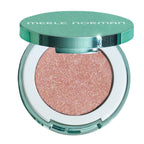 Merle Norman eyeshadow compact with a shimmering rose gold glitter shadow in a round clear case with a metallic mint green lid.