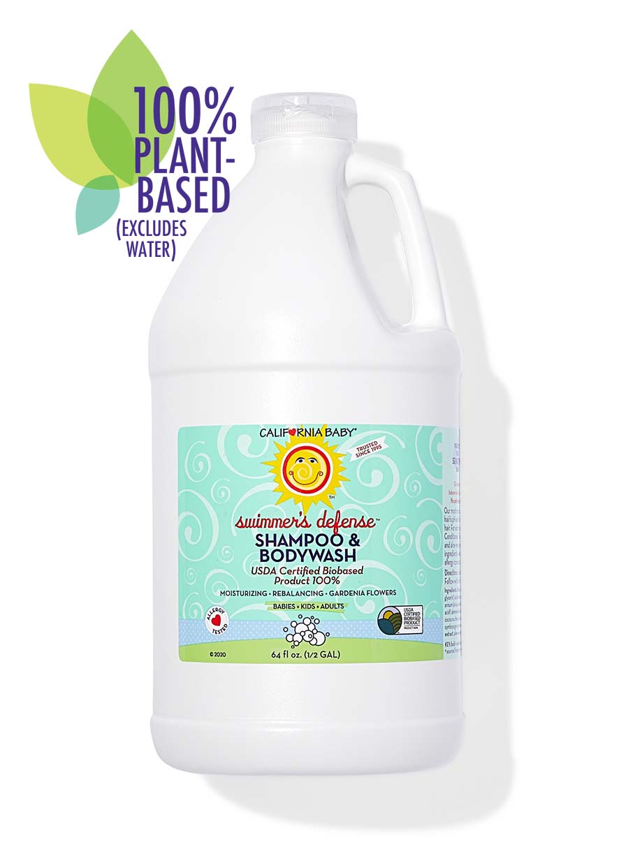 Large white half-gallon bottle of California Baby - Swimmer's Defense™ Shampoo & Bodywash with a light blue label featuring a smiling sun, promoting 100% plant-based ingredients excluding water, ideal for babies, kids, and adults.